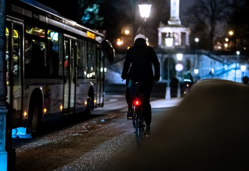cyclist riding alongside the bus in the illuminate